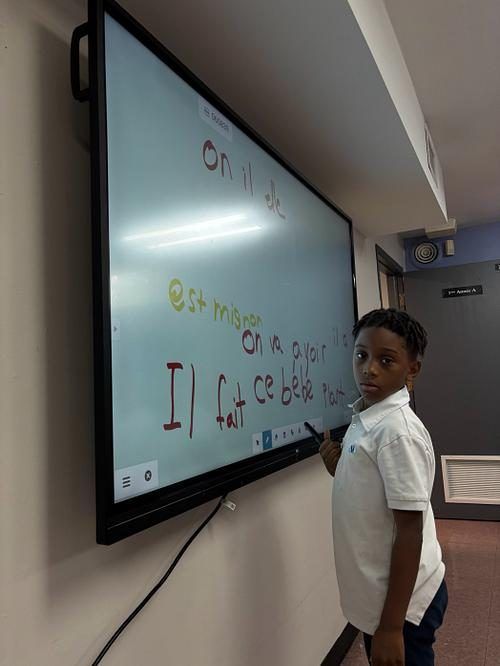 Élève de l'Académie Lavalloise écrivant des phrases au tableau intelligent