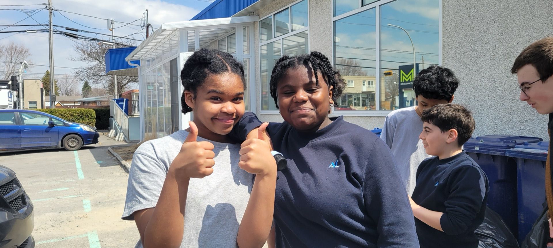 Élèves de l'Académie Lavalloise souriants devant l'école, pouces en l'air