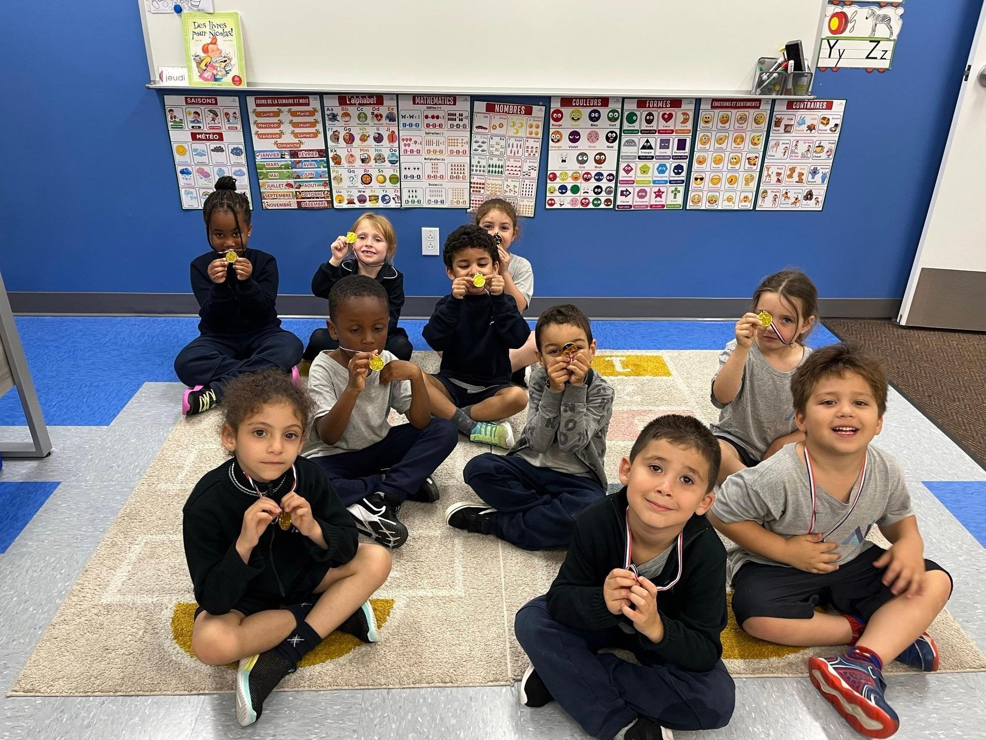 Petit groupe d'élèves de maternelle 4 ans assis sur le tapis, montrant fièrement leur travail