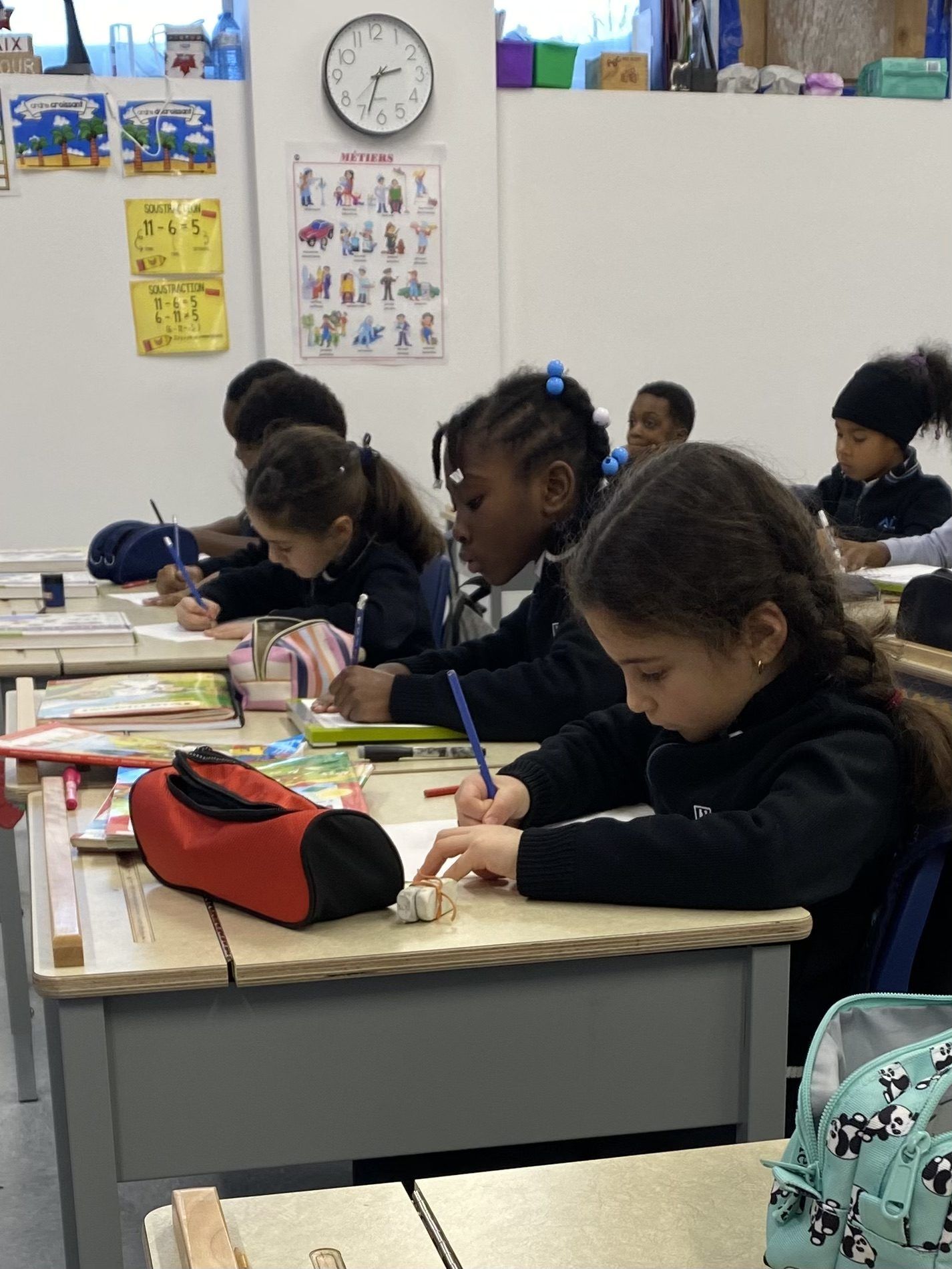 Élèves du primaire concentrés à leur pupitre, en train d'écrire