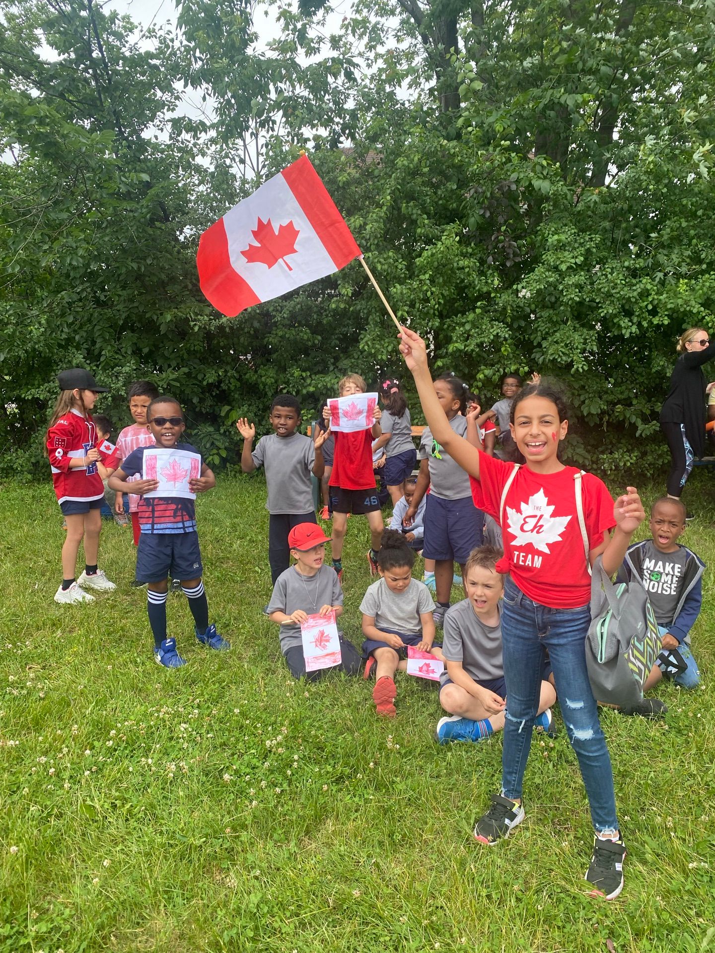 Élèves de toutes origines célébrant dehors avec des drapeaux du Canada