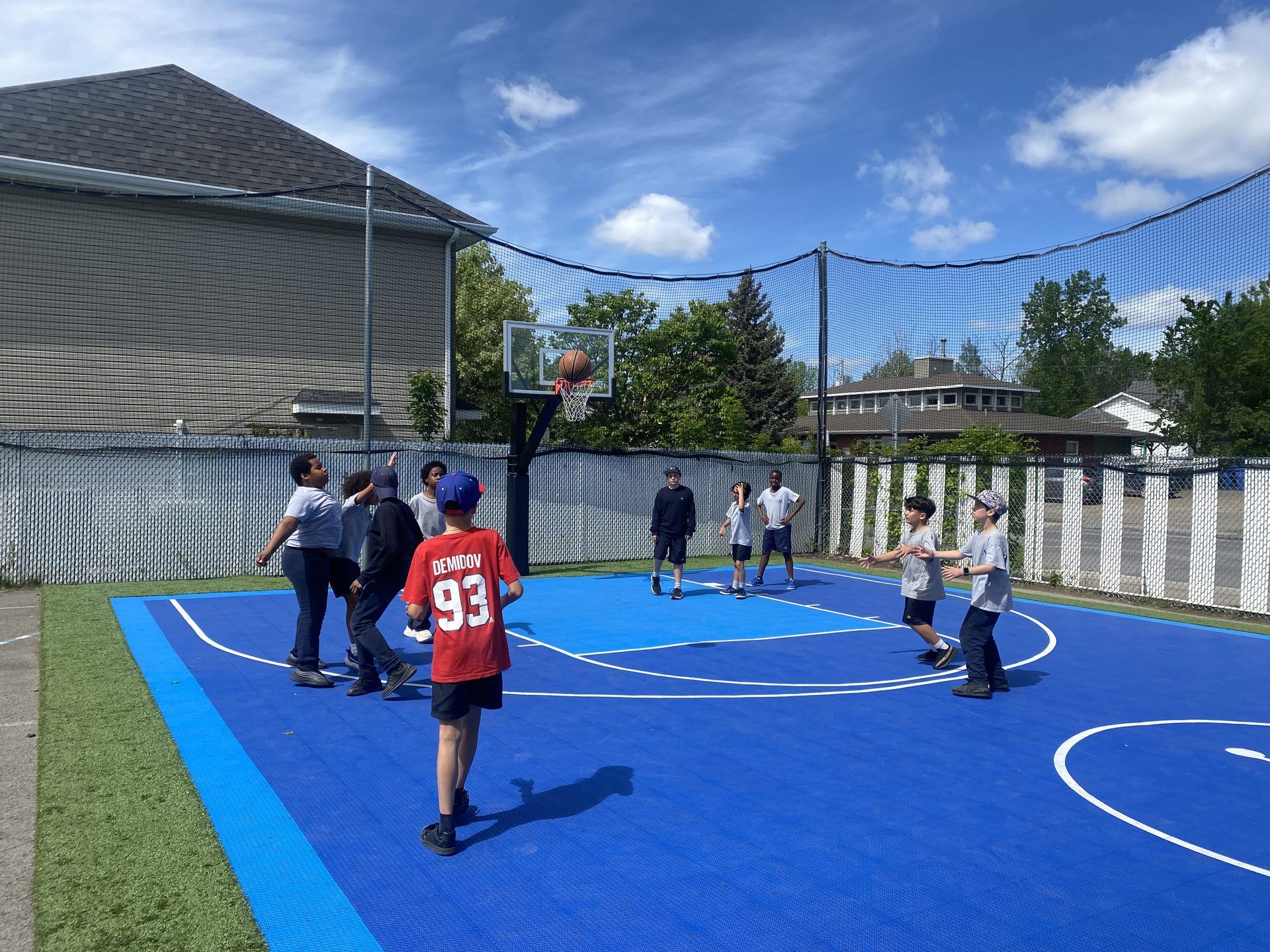 Élèves de l'Académie Lavalloise jouant au basketball sur le terrain extérieur de l'école