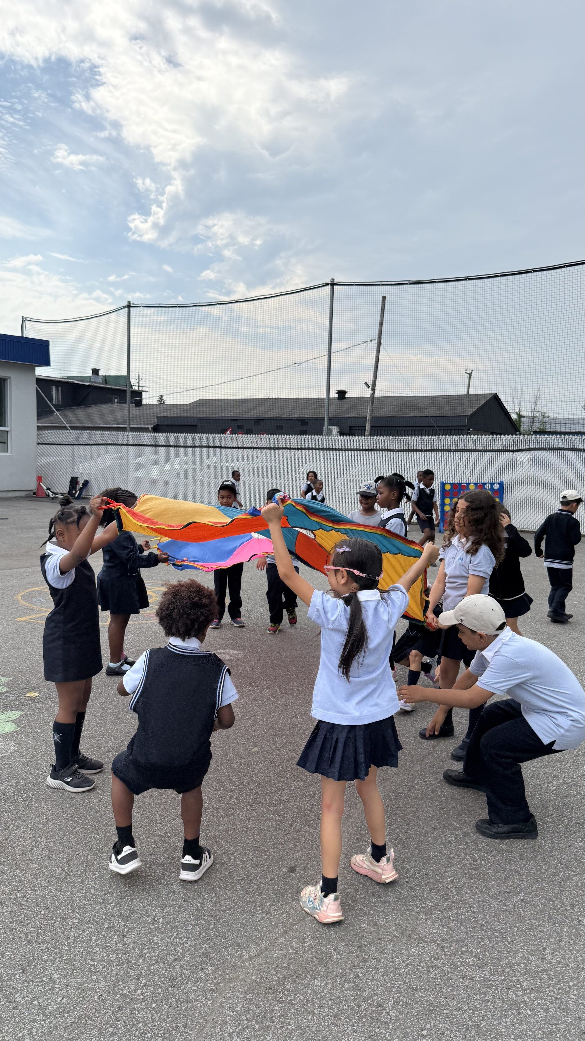 Élèves en uniforme régulier jouant avec un parachute dans la cour d'école